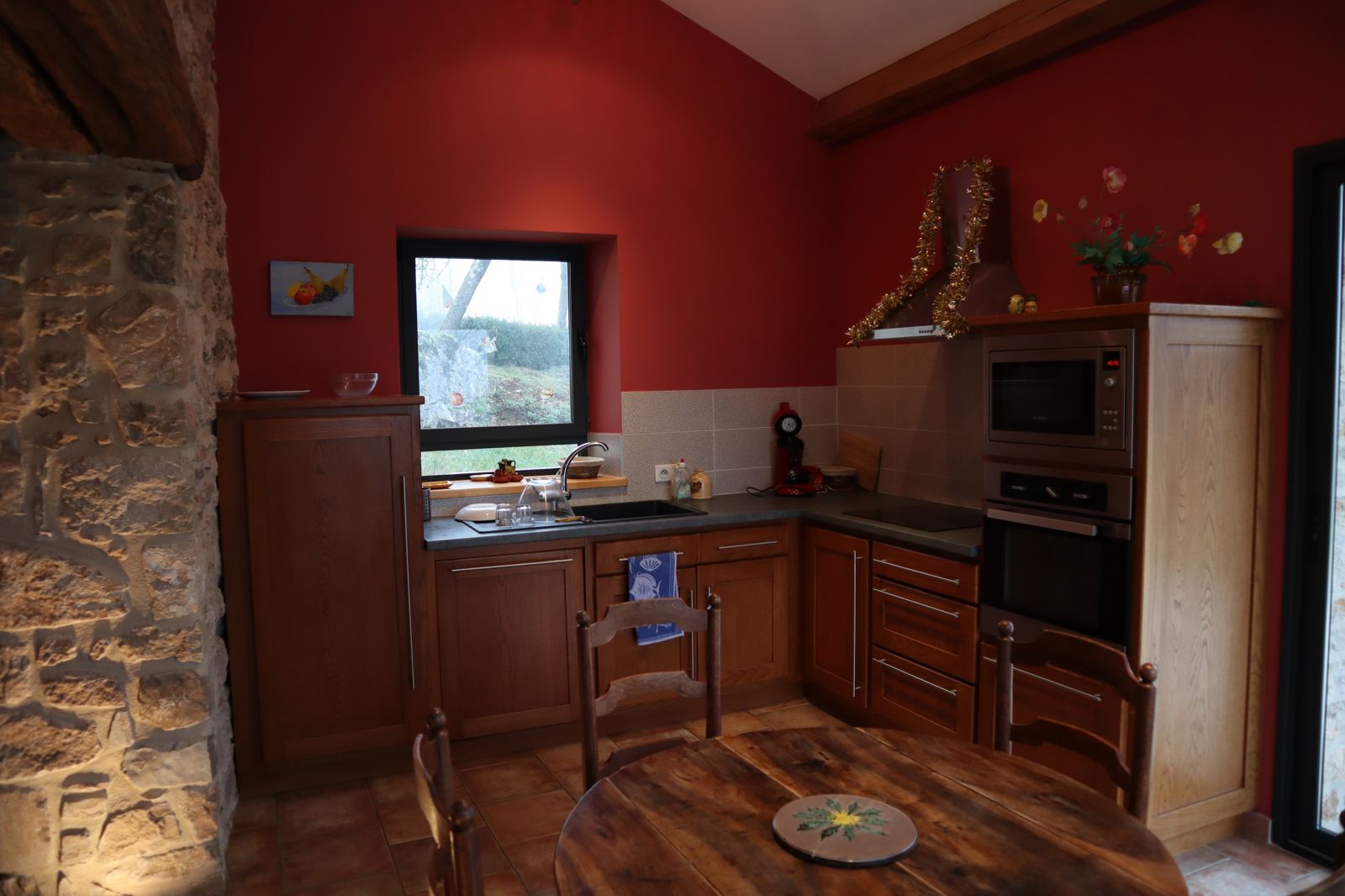Cuisine équipée du gîte Le Rouge Gorge, mur rouge et pierre apparente