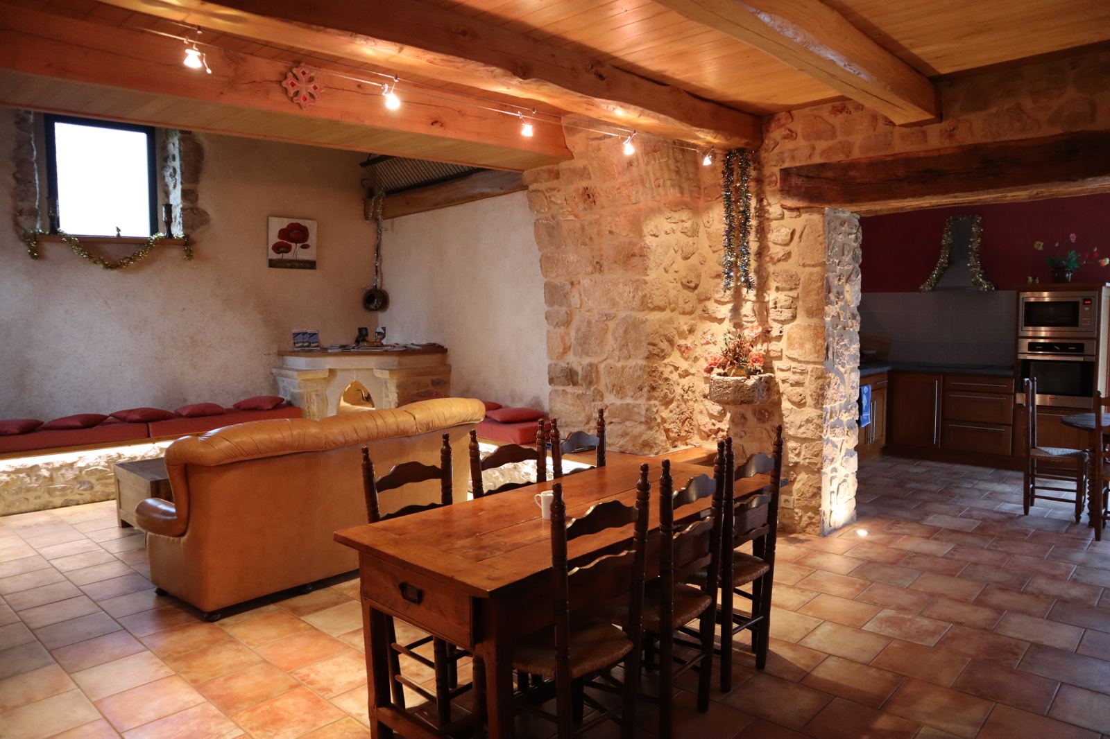 Vue d'ensemble du séjour du gîte, pierre apparente, canapé en cuir et coin repas